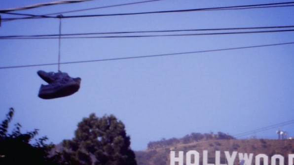 A pair of sneakers hang from a electric cable wire over a street Stock  Photo - Alamy