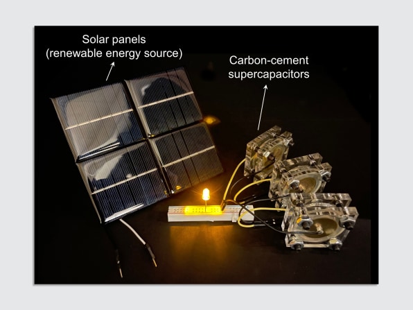 A la izquierda, un panel solar tiene la etiqueta "Panel solar (energía renovable)".  A la derecha, 3 dispositivos rectangulares están etiquetados como "supercondensadores de carbono-cemento".  Están conectados a una placa de pan y se enciende una luz LED.